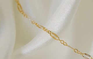 Gold chain necklace on white silk