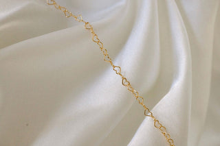 Gold heart chain necklace on white silk