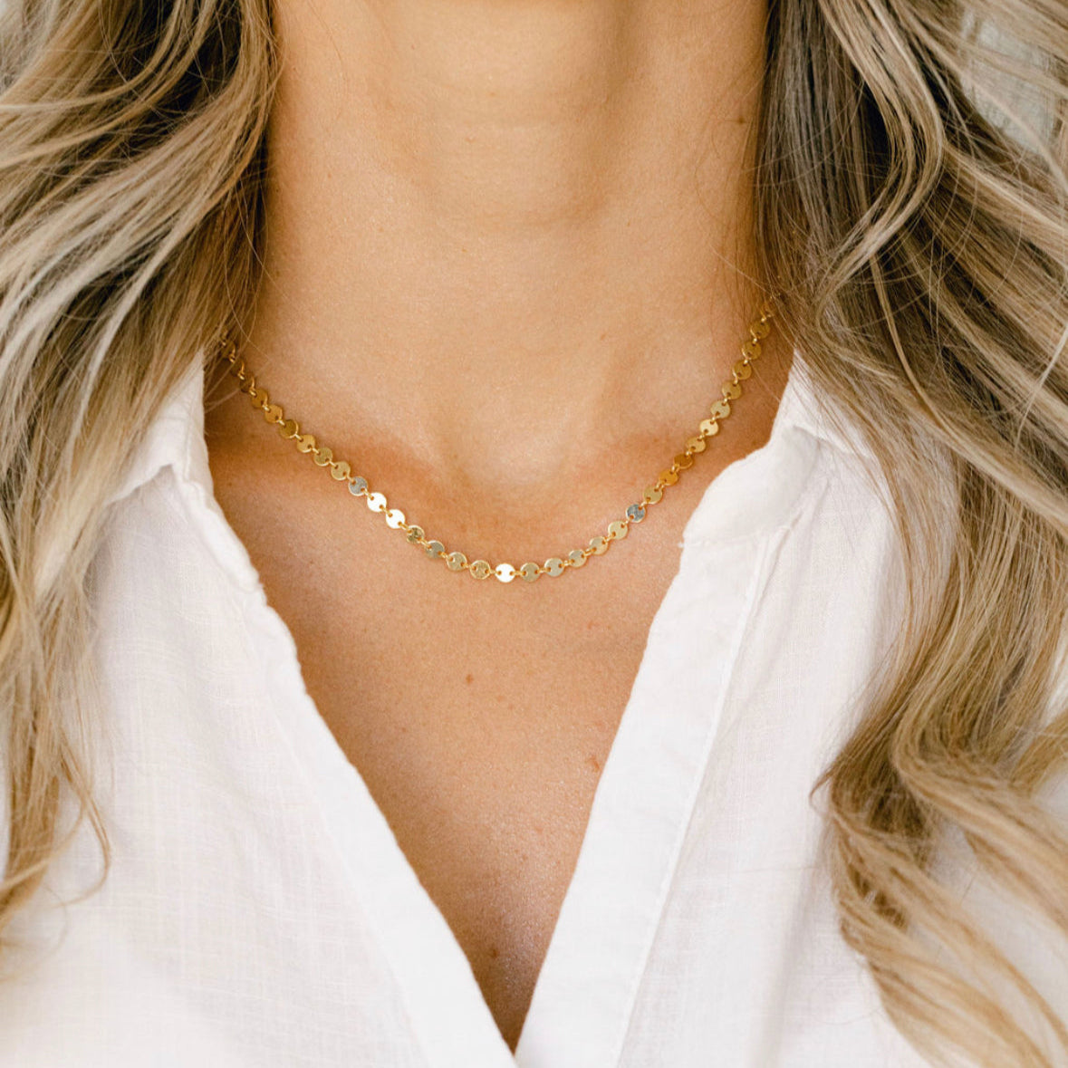 Gold disc necklace on white shirt