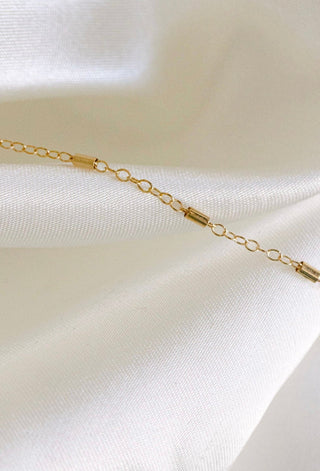 Gold bar chain necklace on white fabric