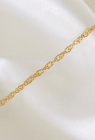 Gold chain necklace on white fabric