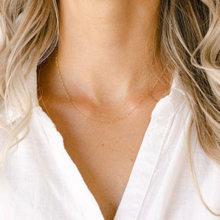 Woman wearing gold necklace with white shirt