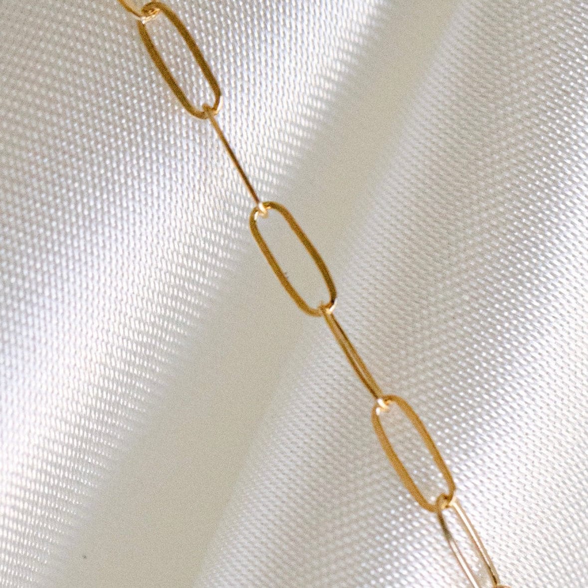Gold chain necklace on white fabric