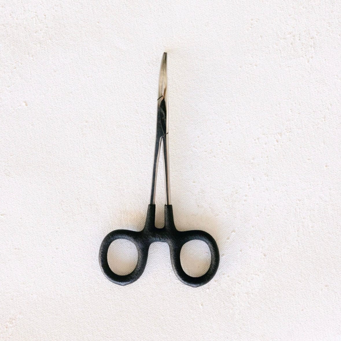 Black surgical forceps on white background
