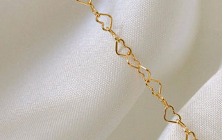 Gold heart chain necklace on white fabric