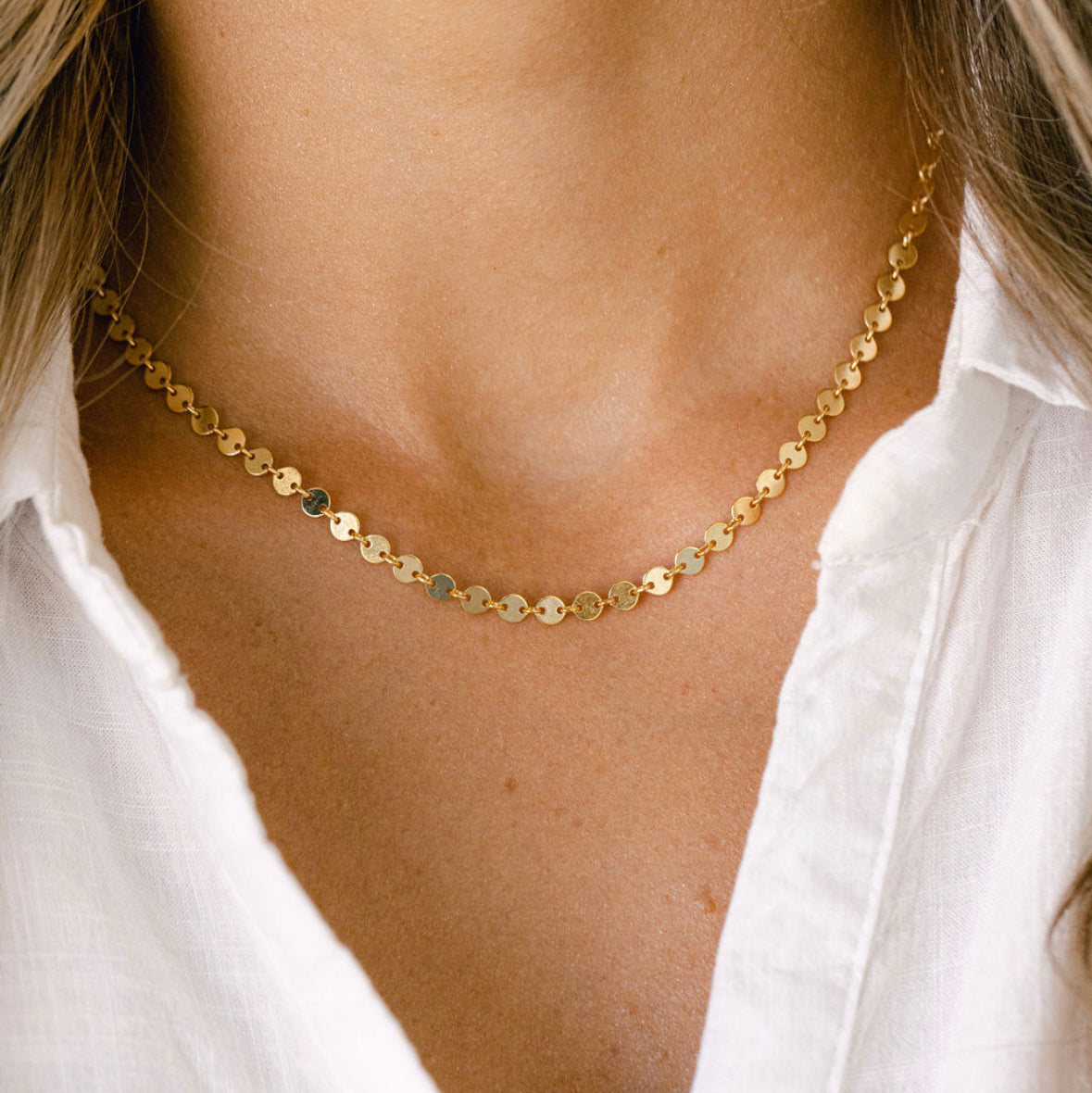 Gold disc necklace on white shirt
