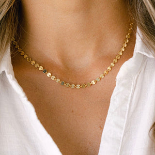 Gold disc necklace on white shirt