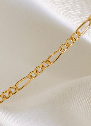 Gold figaro chain necklace on white fabric