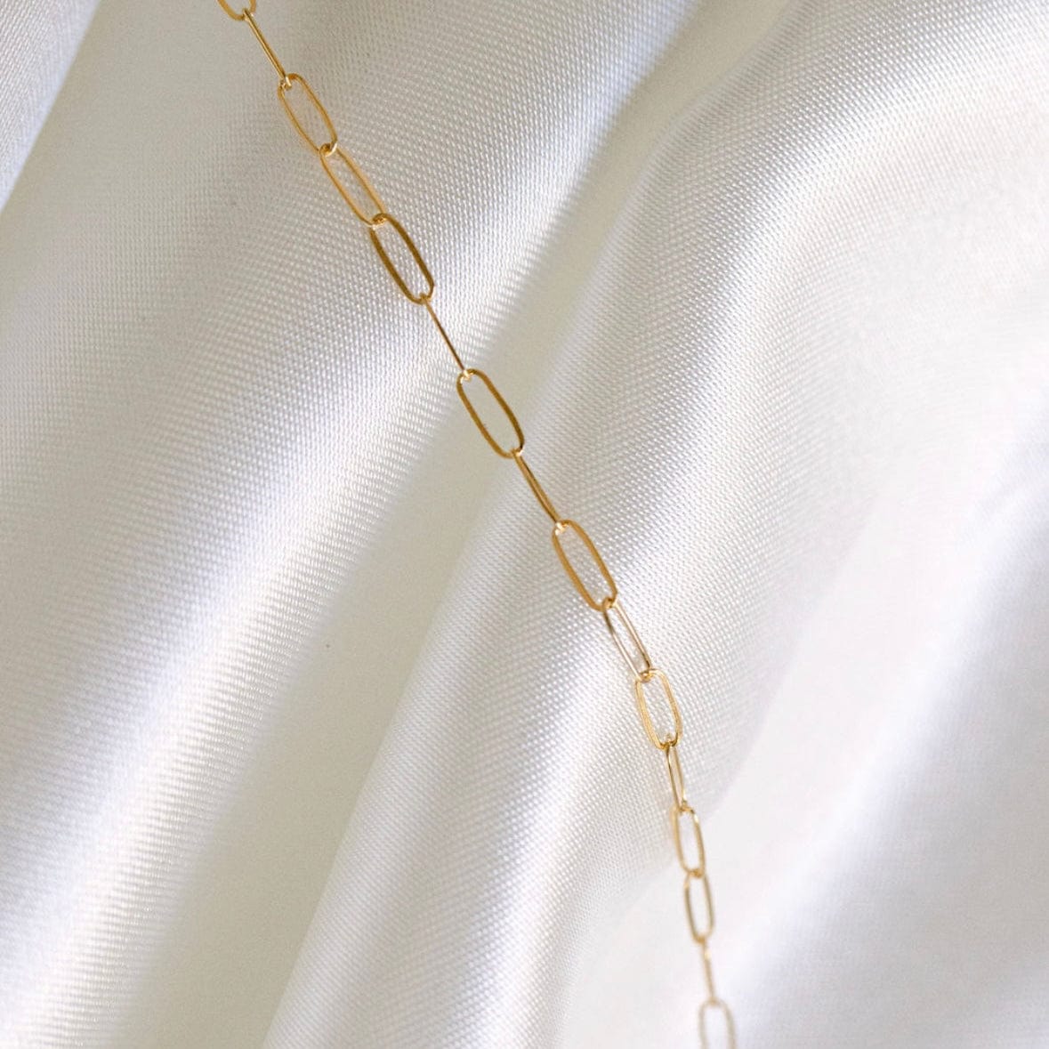 Gold chain necklace on white silk