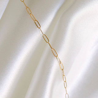 Gold chain necklace on white silk