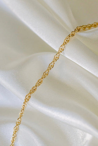 Gold chain necklace on white fabric