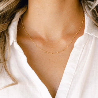 Gold necklace on a woman in white shirt