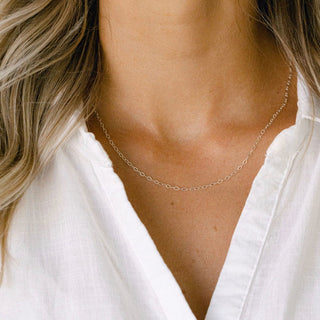 Delicate silver chain necklace on white shirt