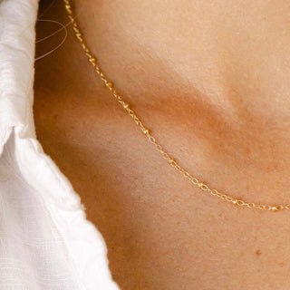 Gold necklace detail on white shirt