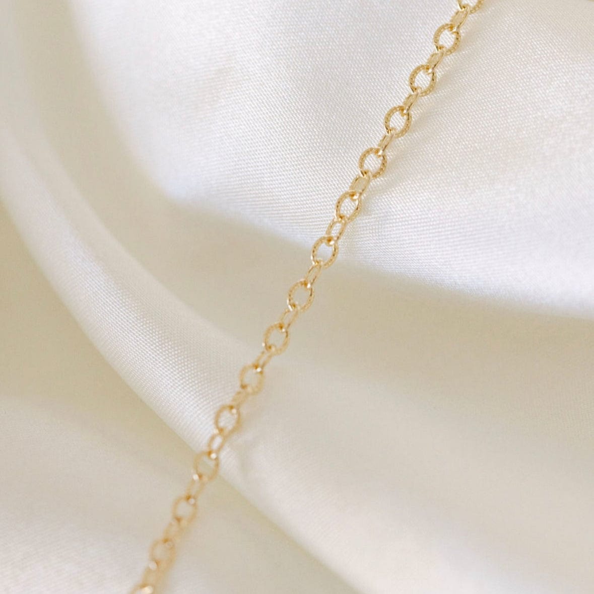 Gold chain necklace on white silk