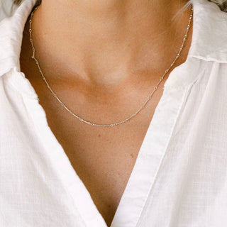 Delicate gold necklace on a white shirt.