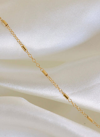 Gold chain necklace on white fabric