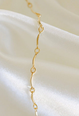 Gold chain necklace on white satin