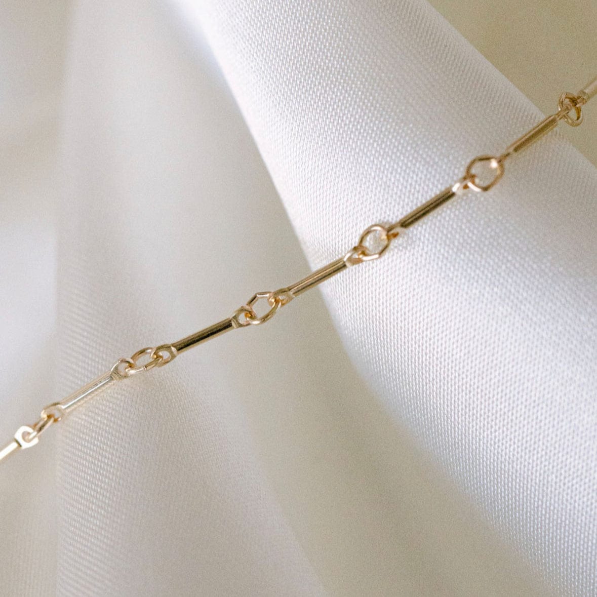 Gold chain necklace on white fabric