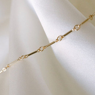 Gold chain necklace on white fabric