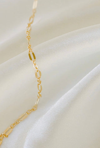 Gold chain necklace on white satin