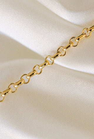 Gold chain necklace on white fabric