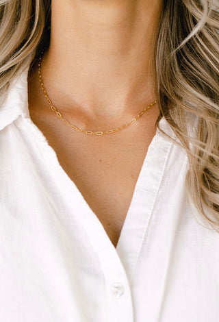 Gold chain necklace on woman in white shirt