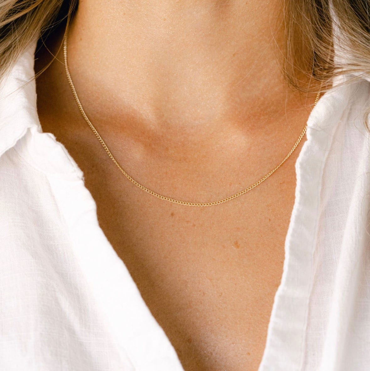 Gold chain necklace on a white shirt