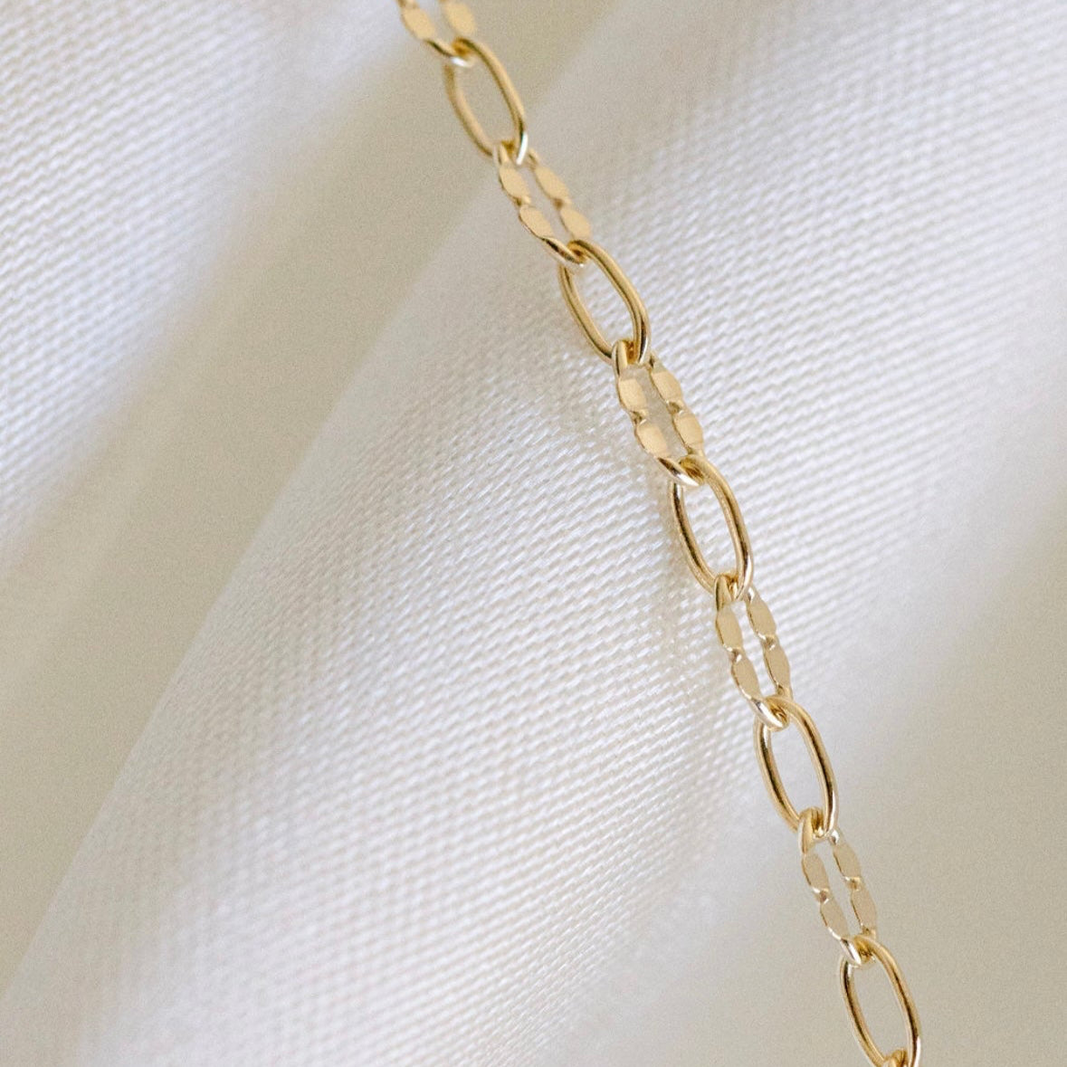 Gold chain necklace on white fabric