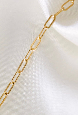Gold chain necklace on white fabric