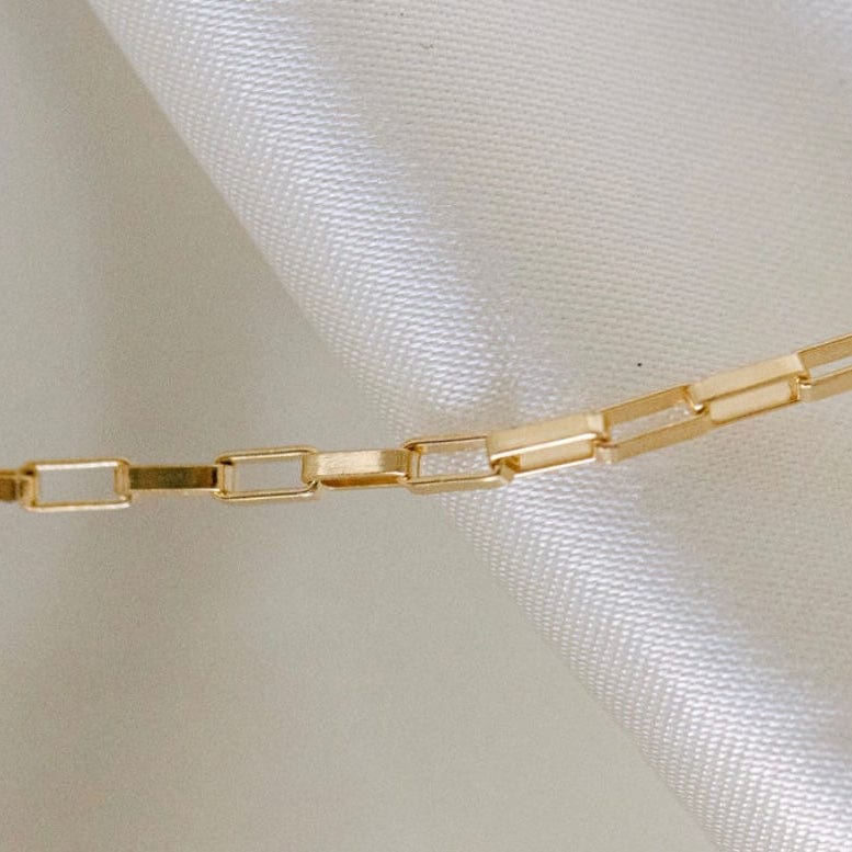 Gold chain necklace on white fabric
