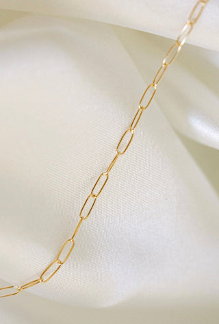 Gold chain necklace on white fabric