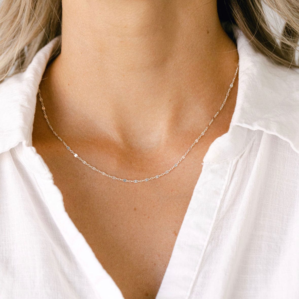 Delicate silver necklace on woman in white shirt