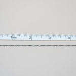 Silver chain next to a ruler on a light gray background
