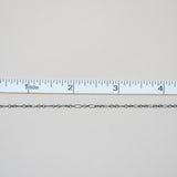 Silver chain next to a ruler on a light gray background