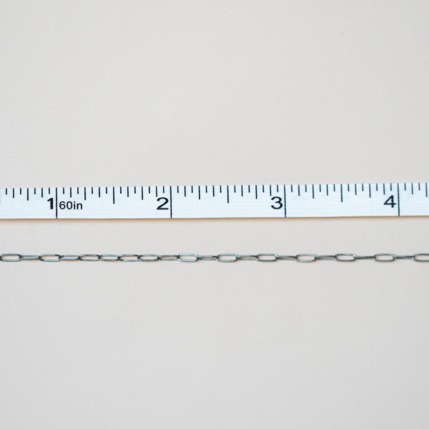 Metal chain with a ruler for scale on a light gray background