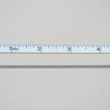 Metallic chain with a ruler for scale on a light gray background