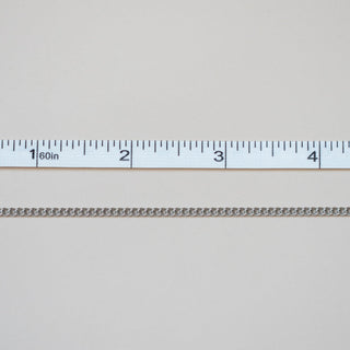 Metallic chain with a ruler for scale on a light gray background