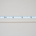 Thin white chain on a light gray background with a ruler for scale.