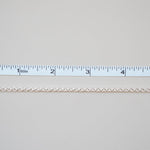 Gold chain next to a ruler on a light gray background