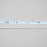 Gold chain next to a ruler on a light gray background