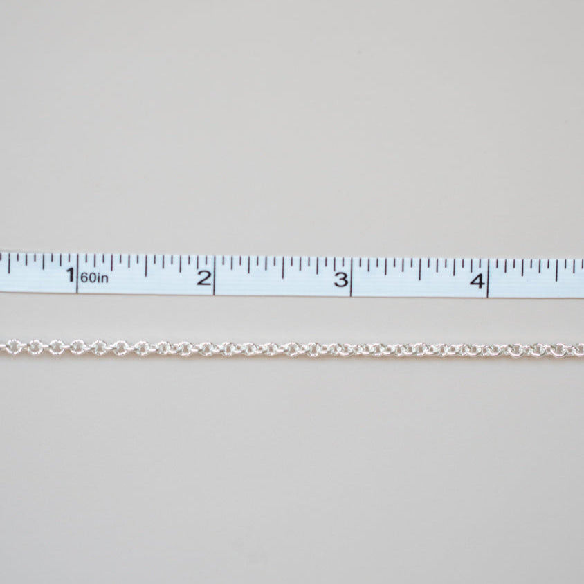 Gold chain next to a ruler on a light gray background