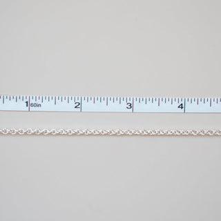 Gold chain next to a ruler on a light gray background