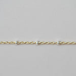 Gold bracelet with small beads on a light gray background