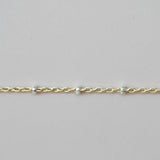 Gold bracelet with small beads on a light gray background