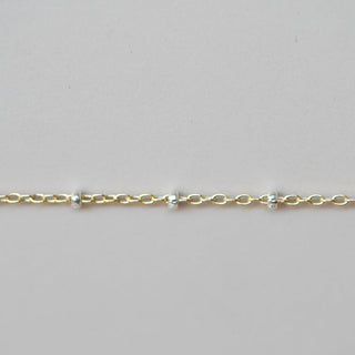 Gold bracelet with small beads on a light gray background