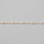 Gold chain bracelet on a light gray background