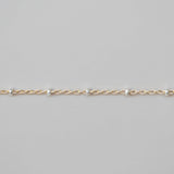 Gold chain bracelet on a light gray background