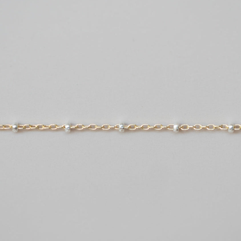 Gold chain bracelet on a light gray background