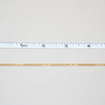 Gold chain with a ruler for scale on a white background